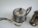 two silver teapots sitting next to each other on a table
