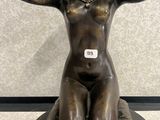 statue en bronze représentant une femme assise sur un rocher, les mains posées sur la tête