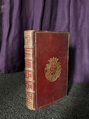 un vieux livre posé sur une table, à côté d'un rideau violet