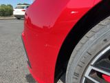 a red car parked in a parking lot with other cars in the background