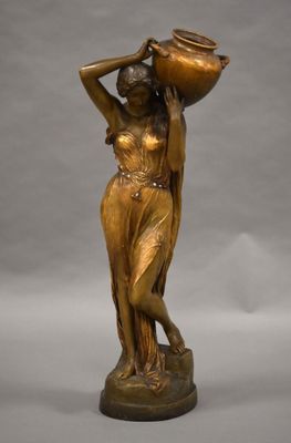 une statue antique en bronze représentant une femme portant un pot sur la tête