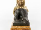 bronze statue of a woman laying on a marble base