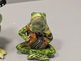 two figurines of frogs that are sitting on a table