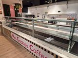 un comptoir en verre sur lequel est accrochée une affiche, dans un café