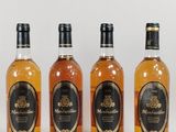 four bottles of whisky are lined up on a white surface