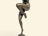 statue en bronze représentant une femme assise sur un rocher, les bras tendus