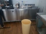 une femme debout dans une cuisine, près d'une poubelle