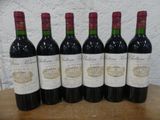 six bouteilles de vin rouge sont alignées sur une table en bois