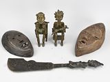 trois figurines en bronze représentant des personnes assises sur un banc, à côté d'un couteau et d'autres objets