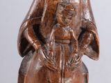 wooden statue of a woman sitting on a stool holding a basket