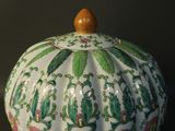 a white vase with a green and pink design on it