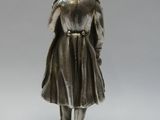 figurine en argent représentant une femme portant un chapeau et un manteau