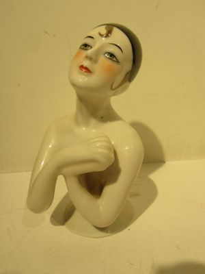 a white figurine of a woman sitting on a table