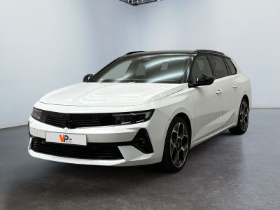 La voiture blanche est garée dans une grande pièce équipée d'un ventilateur de plafond.
