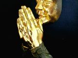 a gold statue of a person holding a praying hand