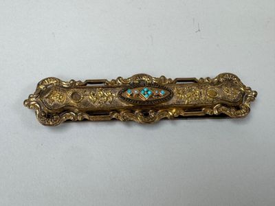 un gros plan sur une broche en or et turquoise