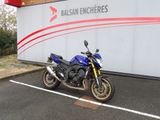 une moto bleue garée devant un immeuble