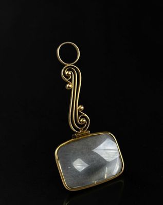 un gros plan d'un pendentif plaqué or orné d'une pierre de quartz facettée
