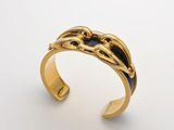 une image représentant un bracelet manchette en or orné d'un motif en noir et blanc