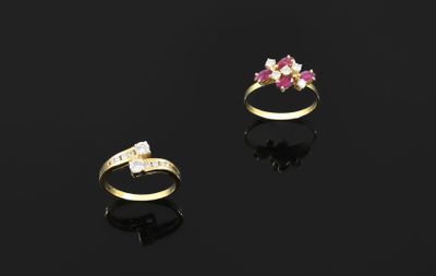 two gold rings with pink and white stones on a black surface