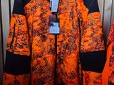 an orange and black jacket hanging on a rack in front of a wooden wall