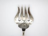 a silver fork with a flower on it on a white surface