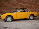 a yellow car that is parked in front of a brick wall