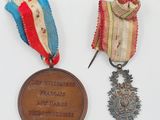 Deux médailles sont posées sur une surface blanche : l'une est une médaille et l'autre est une médaille.