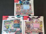 Trois paquets de cartes Pokémon se trouvent dans un paquet posé sur une table
