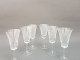 six verres à vin transparents sont alignés sur une table