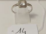 une bague en or blanc sertie d'un diamant taille carrée entouré d'un halo