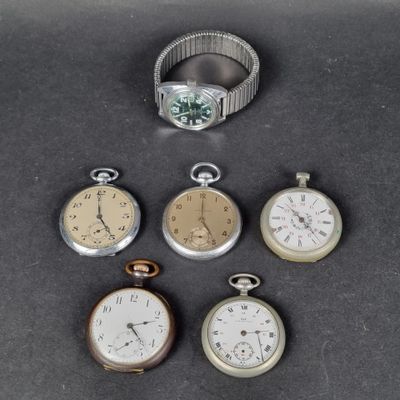 plusieurs modèles différents de montres de poche et une bague posés sur une table