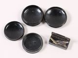 three black bowls and two silver spoons on a white surface