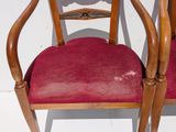 two wooden chairs with red upholstered cushions on them