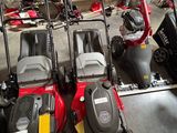 Plusieurs tondeuses à gazon sont alignées en rang dans un garage