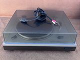 un gros plan d'une platine posée sur une surface recouverte de moquette, avec un cordon d'alimentation