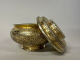 a gold bowl with a lid sitting on a table