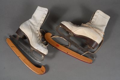 deux paires de patins à glace blancs posées sur une luge en bois