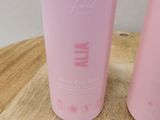 two pink plastic bottles sitting on top of a wooden table