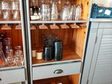 bottles and glasses on a shelf in a kitchen with tile flooring