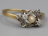 a close up of a ring with a pearl and diamonds on it