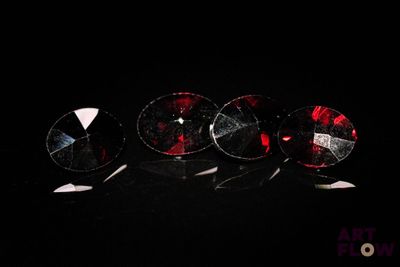 trois paires de boucles d'oreilles en verre rouge et blanc posées sur un fond noir