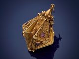 a close up of a gold pendant on a blue surface