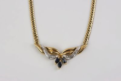 une photo d'un collier en or orné d'une pierre bleue