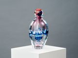 une bouteille en verre posée sur un socle