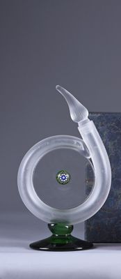 a glass vase with a bird on it next to a box