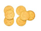 plusieurs pièces d'or sur une surface blanche, avec une pièce d'or au premier plan
