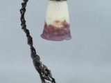 une lampe à l'ancienne avec un abat-jour en verre posée sur un pied en métal