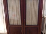 a wooden cabinet with two glass doors and a radiator in the corner