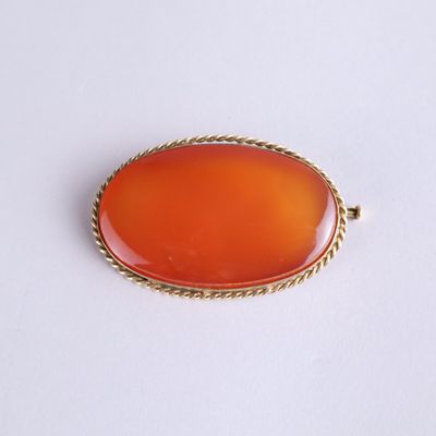 une image représentant un pendentif ovale de couleur orange entouré d'une corde